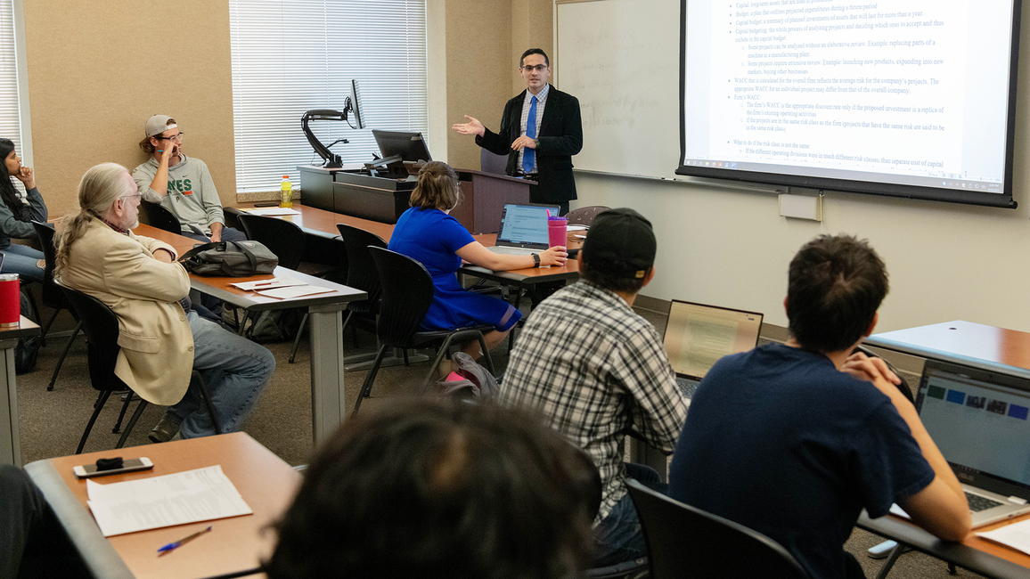 Professor Serkan Karadas teaches a class with seven students visible in the photo.