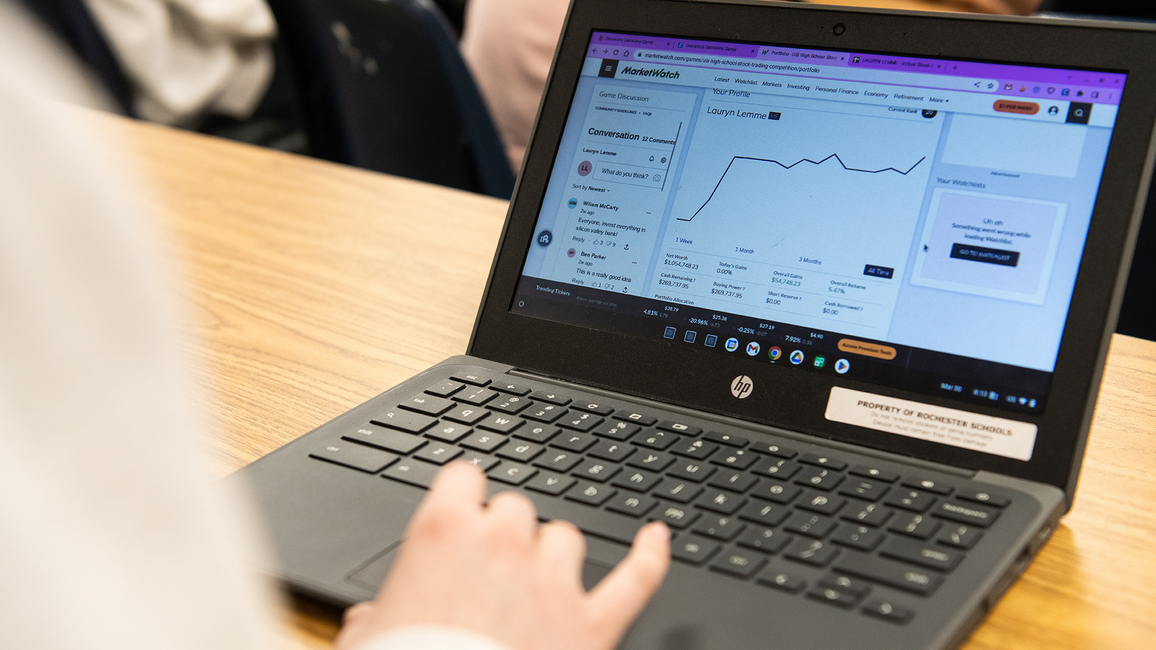 A hand on a laptop computer with the screen showing the MarketWatch platform.