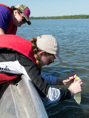 two students sampling water from a lake