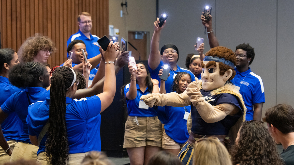 Orientation leaders dance around UIS mascot Orion at a First-Year Student Orientation event.