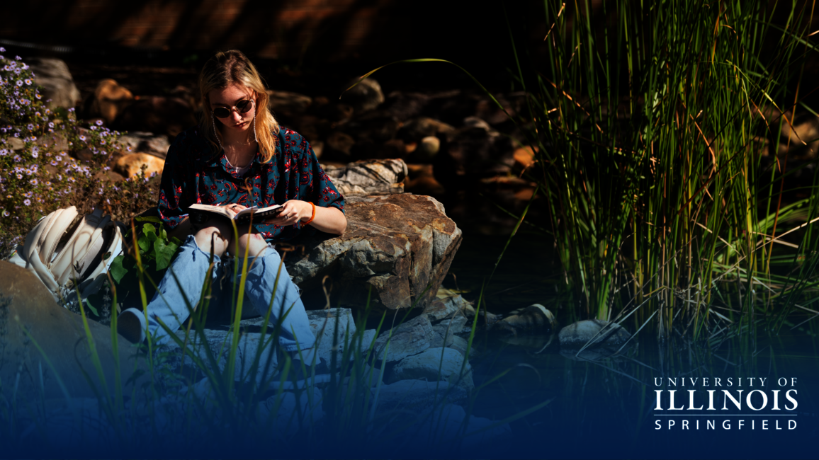 Student reading by the Koi Pond.