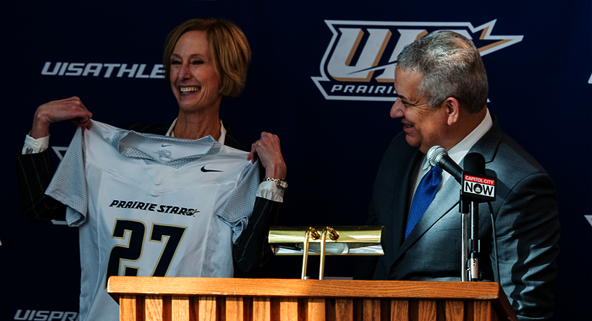 Chancellor Janet Gooch holds up a UIS women's flag football jersey with Athletic Director Mike Herman.