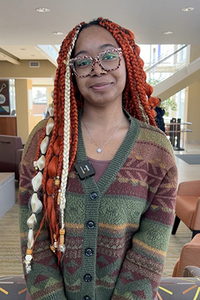 Smiling person with glasses in a warm-toned room.