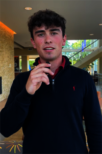 Young man holding a microphone in a modern lobby.