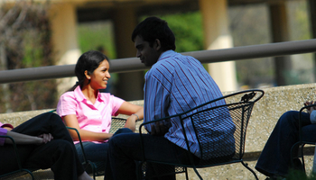 four students sitting out on the quad talking with each other