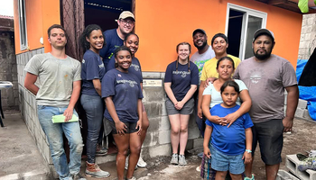 A group of UIS students and local residents stand in front of a newly built home during a service trip in Guatemala.