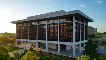 Horace Mann building in downtown Springfield at sunset, with trees and sidewalks in the foreground.
