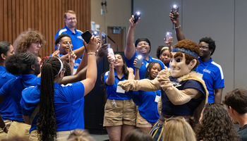 Orientation leaders dance around UIS mascot Orion at a First-Year Student Orientation event.