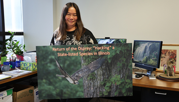 Woman in an office holding a large art print of an osprey.
