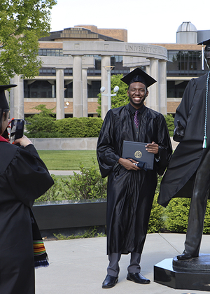 Grad taking photo next to Lincoln Statue