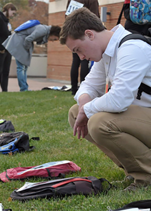 Student looking at backpack on the ground