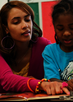 A teacher reading with a student..