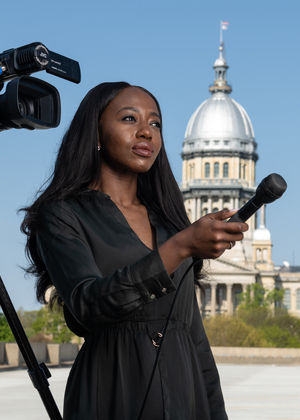PAR student with camera and microphone in front of Illinois Capitol.