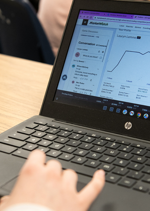 A hand on a laptop computer with the screen showing the MarketWatch platform.