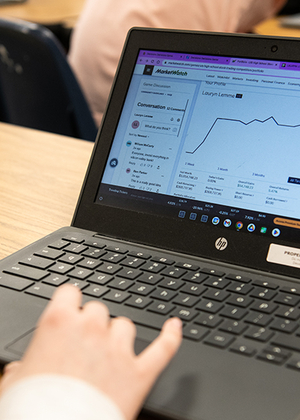 A hand on a laptop computer with the screen showing the MarketWatch platform.