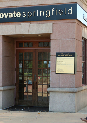A sign on a building reads Innovate Springfield University of Illinois Springfield as two people walk past
