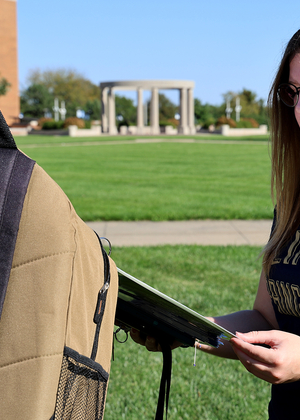 A student reads a story about suicide attached to a backpack on the quad.