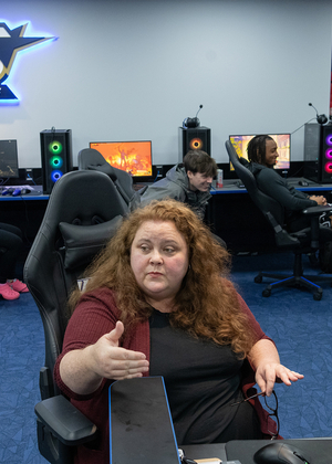 An instructor speaks to students sitting in gaming chairs in the Esports Arena.