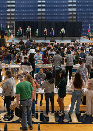 People line up for food as performances take place on stage.