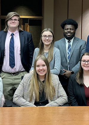 A group of Mock Trial students pose in a courtroom.