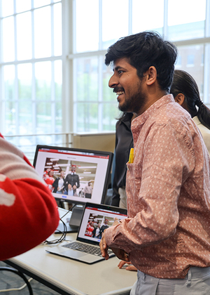 Student smiles while presenting a project on a laptop during a campus event.