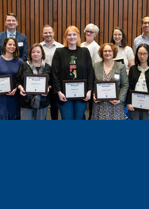 Ten faculty members pose for a photo holding their awards. 
