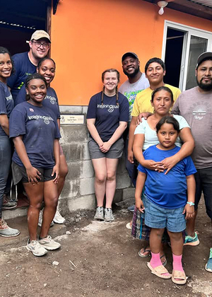 A group of UIS students and local residents stand in front of a newly built home during a service trip in Guatemala.
