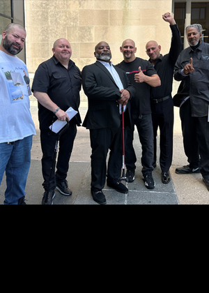 Six men stand smiling outside a courthouse, some raising fists. Left to right: Daniel Rodriguez, Fernando Gomez, Michael McCastle, Gregorio Cardona, Robert Cardona, Lowell Higgins-Bey.