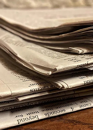 A stack of newspapers on a desk.