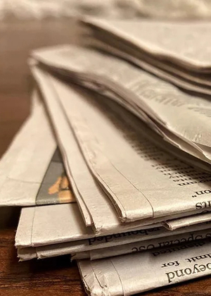 A stack of newspapers on a desk.