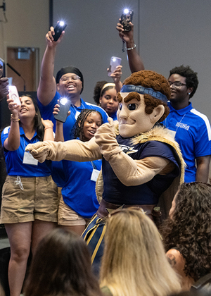 Orientation leaders dance around UIS mascot Orion at a First-Year Student Orientation event.