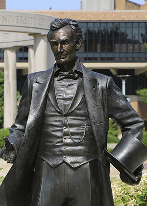 Statue of Abraham Lincoln with the UIS colonnade in the background.