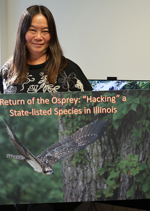 Woman in an office holding a large art print of an osprey.