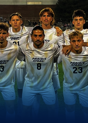 Soccer team posing in white uniforms on a field at night.