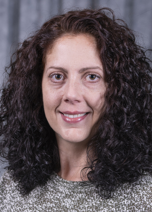 Smiling woman with curly hair on a dark blurred background.