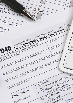 Tax forms with a calculator, pen, and keyboard.