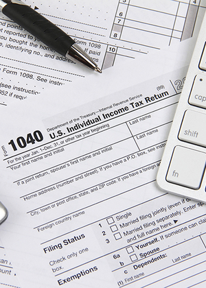 1040 tax form with a pen and computer keyboard.