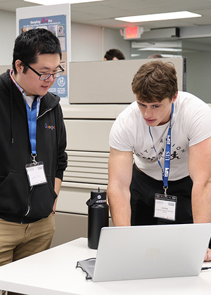 Two men collaborating at a laptop in an office setting.