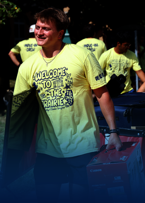Students in yellow shirts moving carts outdoors.