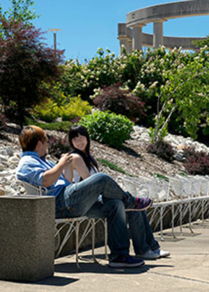 Two people relaxing on a sunny outdoor path with greenery.