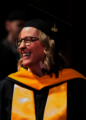 Graduate in cap and gown smiling during ceremony.