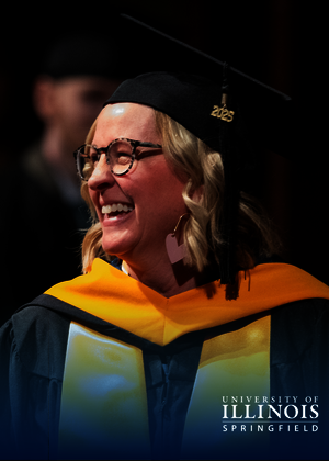 Graduate in cap and gown smiling at a ceremony.