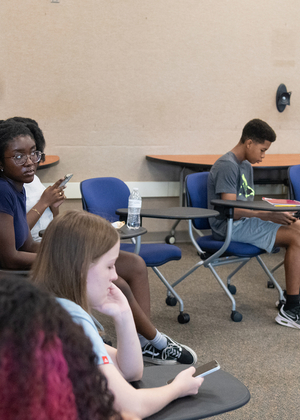 Group discussion in classroom, teacher and students engaged.