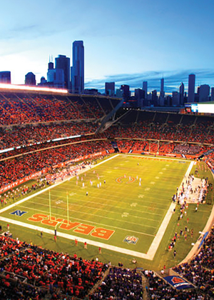 Wide-angle view of a football stadium at dusk, city skyline in the background.