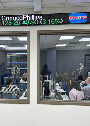 People in a conference room watching a financial presentation.
