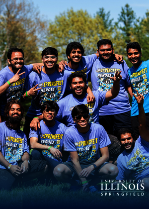 A group of smiling people in matching purple shirts outdoors.
