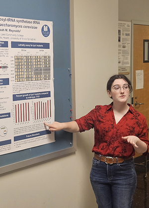 Woman presenting a research poster in a classroom setting.