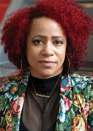 A woman with curly red hair, wearing a floral jacket and hoop earrings.