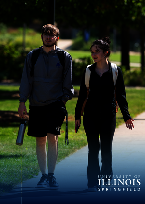 Two students walking on a sunny university campus path, smiling, with backpacks.