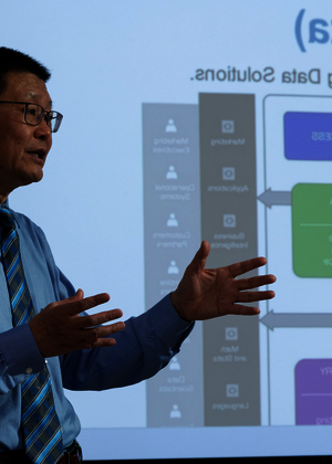 Man presenting data flowchart on screen.